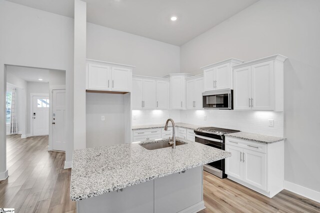 kitchen featuring sink, an island with sink, white cabinets, and appliances with stainless steel finishes