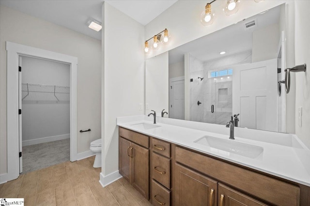 bathroom featuring a shower with door, vanity, and toilet