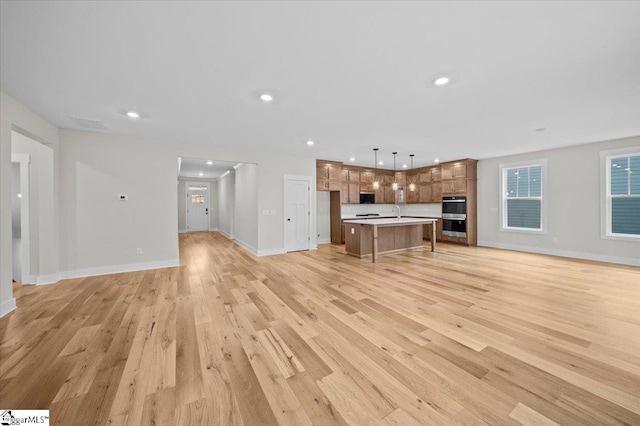 unfurnished living room with sink and light hardwood / wood-style flooring