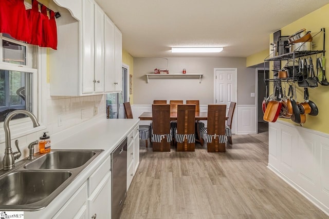 kitchen featuring decorative backsplash, white cabinets, dishwasher, light hardwood / wood-style flooring, and sink