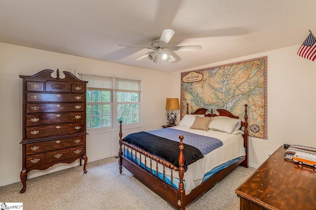 bedroom featuring ceiling fan, light colored carpet, and a textured ceiling