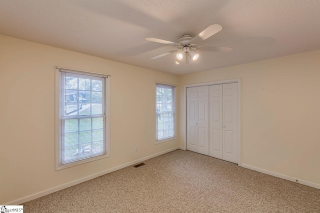 unfurnished bedroom with a closet, ceiling fan, carpet flooring, and a textured ceiling