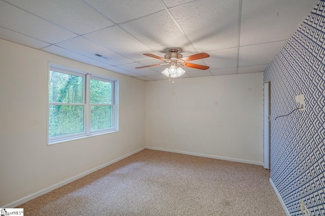 carpeted empty room with ceiling fan and a paneled ceiling