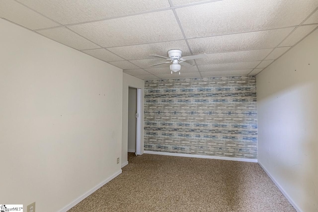 carpeted empty room featuring ceiling fan and a paneled ceiling