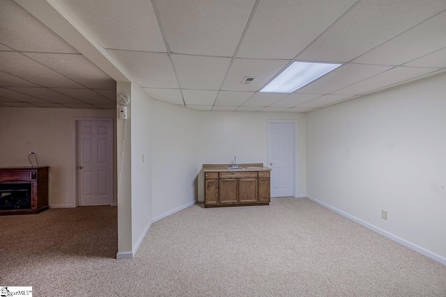 basement with a drop ceiling and light colored carpet