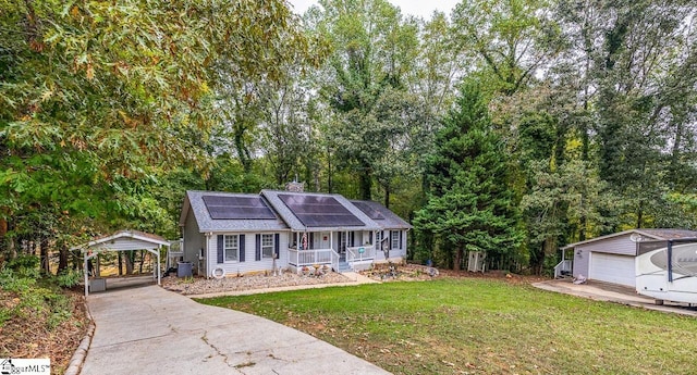 view of front of property featuring a garage, an outdoor structure, solar panels, a front lawn, and covered porch