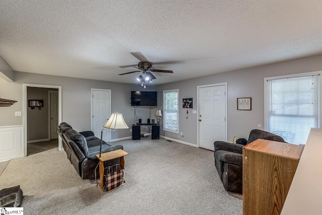 living room featuring ceiling fan, light colored carpet, and a textured ceiling