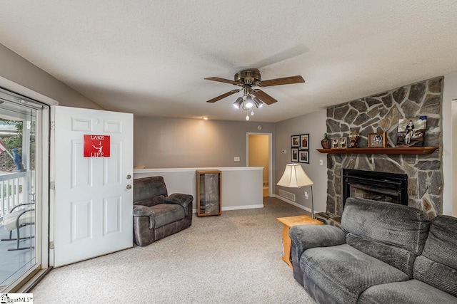 living room featuring a textured ceiling, a fireplace, carpet flooring, and ceiling fan