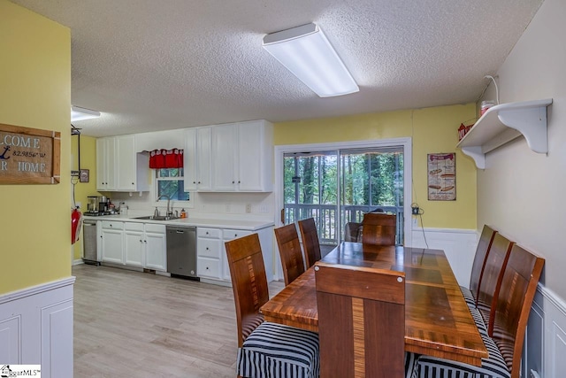 dining area with sink, light hardwood / wood-style floors, and a textured ceiling