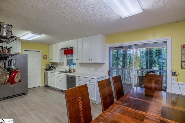 kitchen featuring sink, a textured ceiling, white cabinetry, stainless steel appliances, and light wood-type flooring