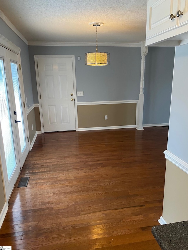 unfurnished dining area with a textured ceiling, dark hardwood / wood-style floors, and crown molding