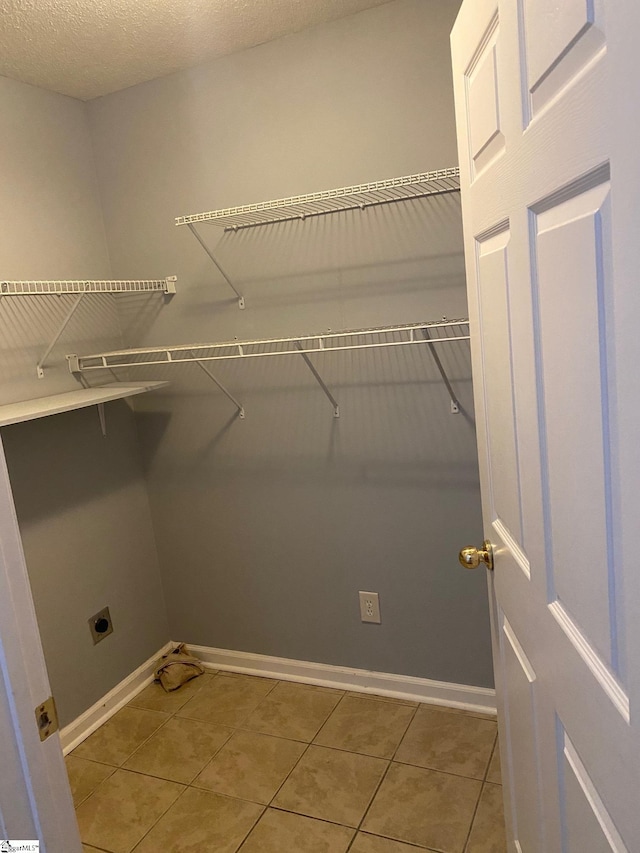 laundry area with tile patterned flooring, a textured ceiling, and electric dryer hookup