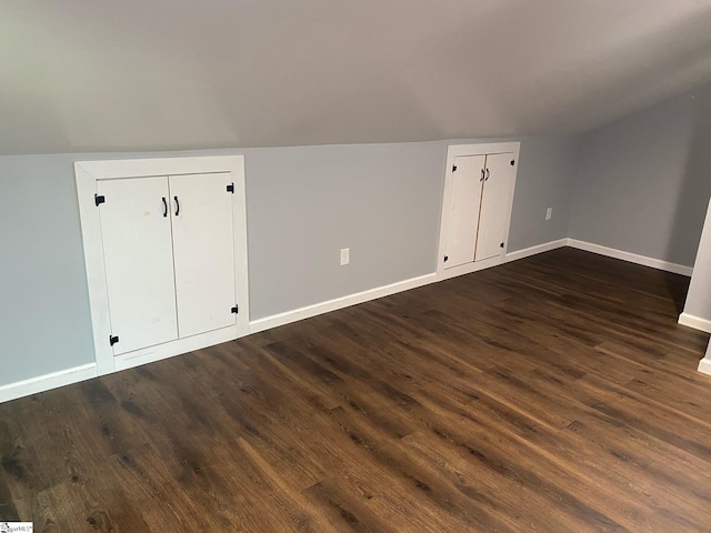 additional living space featuring vaulted ceiling and dark wood-type flooring