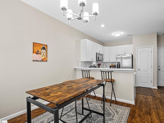 dining area featuring a notable chandelier, dark wood-type flooring, and sink