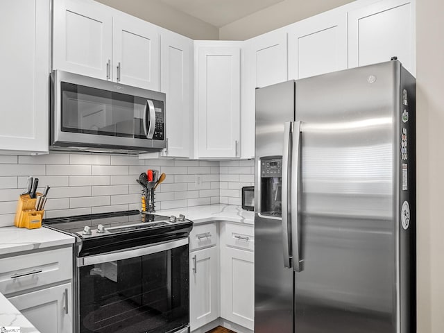 kitchen featuring appliances with stainless steel finishes, tasteful backsplash, light stone counters, and white cabinets