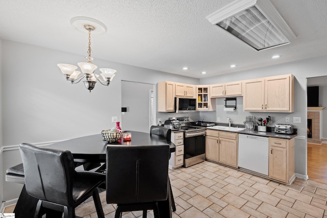 kitchen with sink, a notable chandelier, hanging light fixtures, stainless steel appliances, and light brown cabinetry