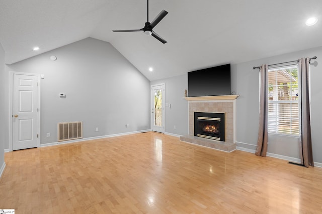 unfurnished living room with light wood-type flooring, vaulted ceiling, ceiling fan, and a tile fireplace