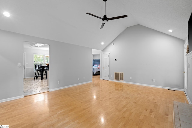 unfurnished living room with ceiling fan with notable chandelier, light wood-type flooring, a textured ceiling, and high vaulted ceiling