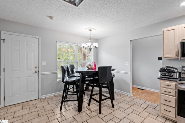 dining space with an inviting chandelier, light hardwood / wood-style floors, and a textured ceiling