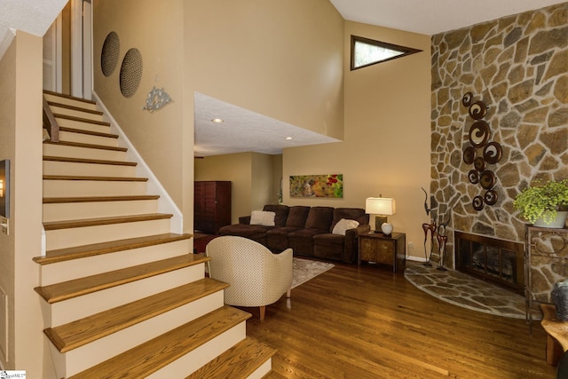 interior space featuring a stone fireplace, a towering ceiling, and hardwood / wood-style floors