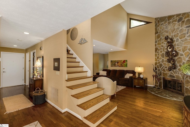 stairway with a textured ceiling, a fireplace, and hardwood / wood-style flooring