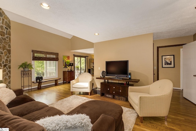 living room with a textured ceiling, vaulted ceiling, and hardwood / wood-style floors