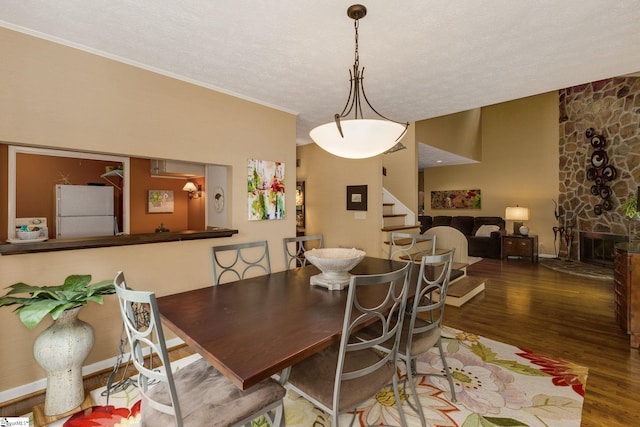 dining space featuring ornamental molding, a textured ceiling, a fireplace, and hardwood / wood-style floors