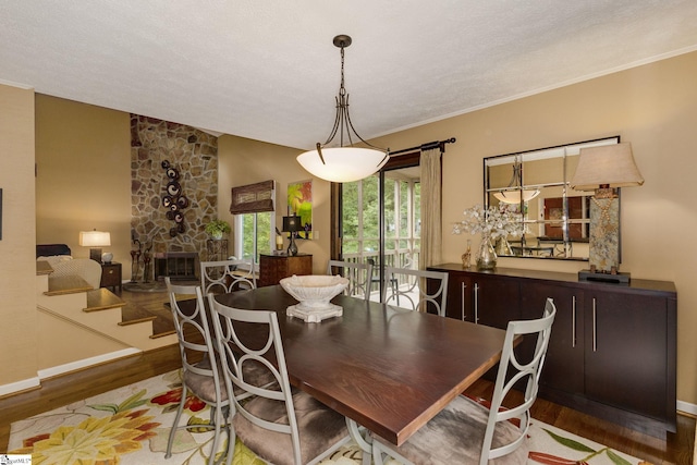 dining space with lofted ceiling, a textured ceiling, a fireplace, crown molding, and hardwood / wood-style floors