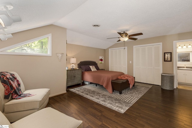 bedroom with ceiling fan, lofted ceiling, ensuite bath, and dark wood-type flooring