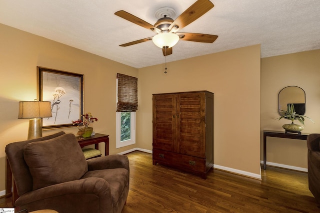 living room featuring ceiling fan, a textured ceiling, and dark wood-type flooring