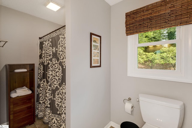 bathroom with a textured ceiling, tile patterned flooring, and toilet