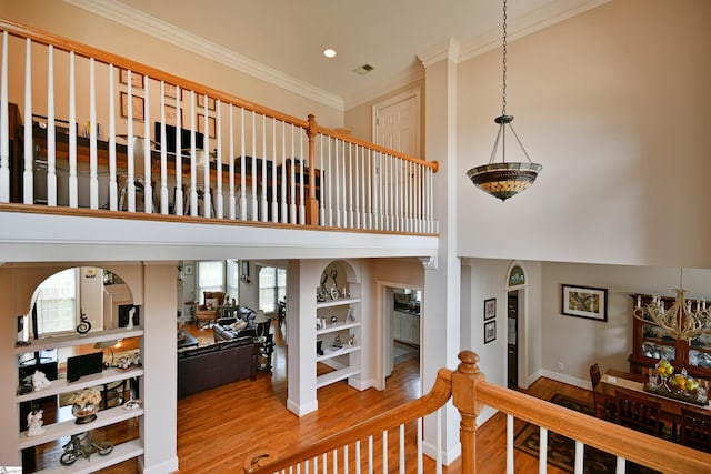 stairs with a healthy amount of sunlight, crown molding, and wood-type flooring