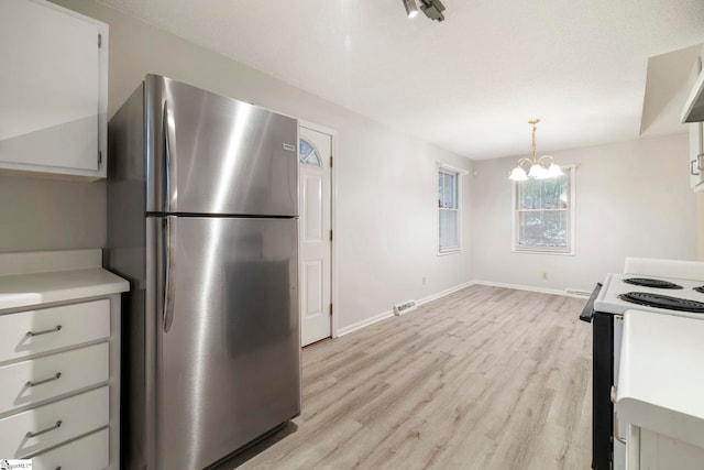 kitchen featuring pendant lighting, a chandelier, white cabinets, white range with electric cooktop, and stainless steel fridge