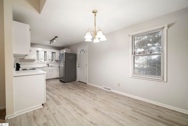 kitchen featuring light hardwood / wood-style floors, white cabinetry, stainless steel refrigerator, an inviting chandelier, and decorative light fixtures