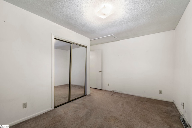 unfurnished bedroom featuring carpet floors, a textured ceiling, and a closet