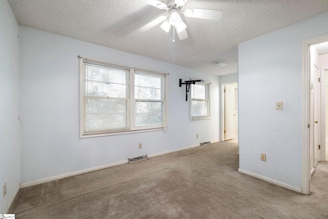 carpeted empty room with ceiling fan and a textured ceiling