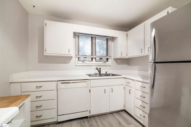 kitchen with sink, white cabinetry, stainless steel refrigerator, dishwasher, and light hardwood / wood-style floors