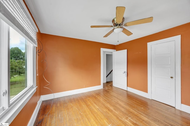 unfurnished room featuring a healthy amount of sunlight, ceiling fan, and light hardwood / wood-style flooring