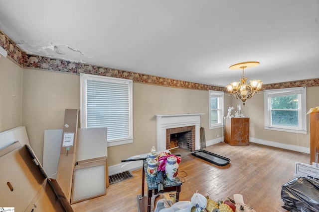 living room featuring light wood-type flooring, a fireplace, and a chandelier