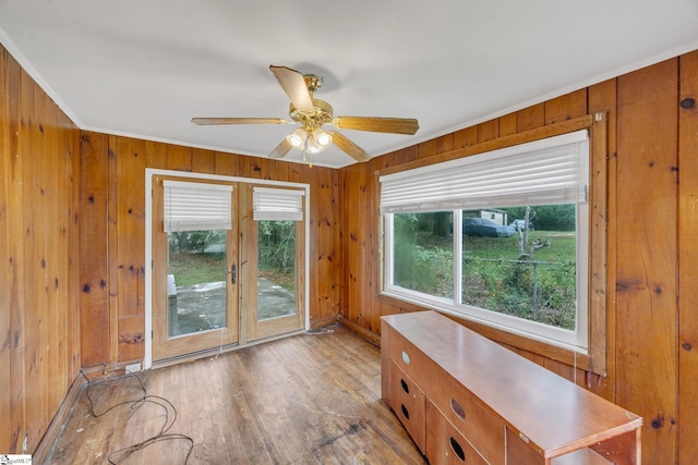 interior space with ornamental molding, wooden walls, ceiling fan, and light hardwood / wood-style flooring