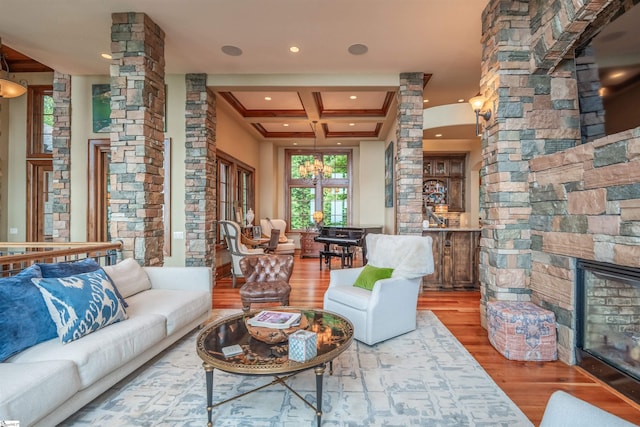 living room with hardwood / wood-style flooring, beam ceiling, decorative columns, coffered ceiling, and a fireplace