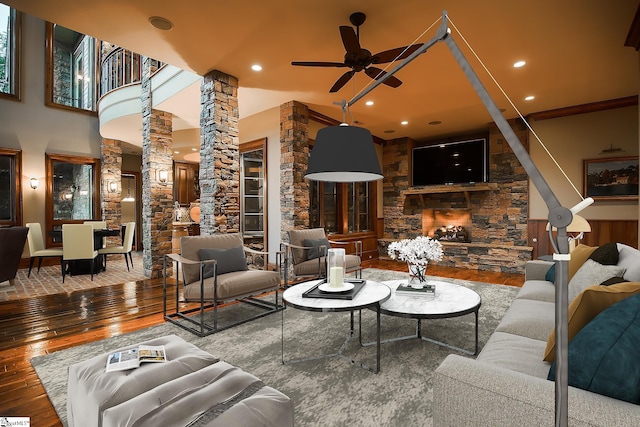 living room featuring wood-type flooring, decorative columns, and ceiling fan