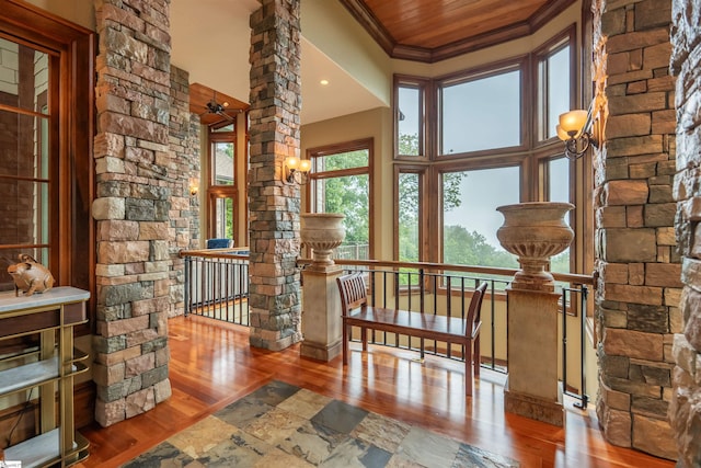 interior space with ornamental molding, a high ceiling, wooden ceiling, and hardwood / wood-style floors