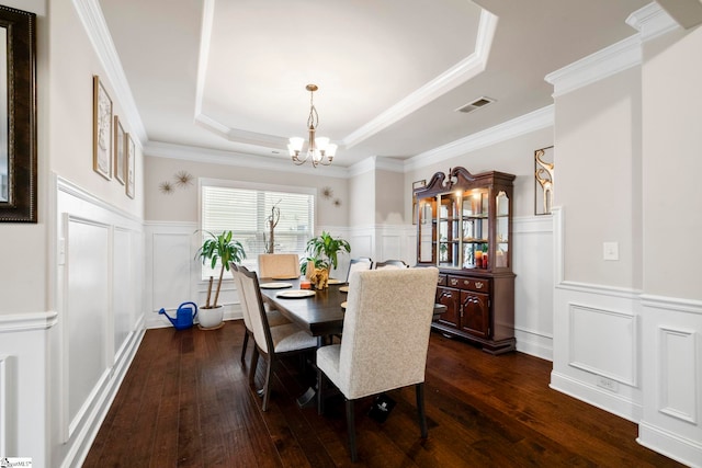 dining room featuring ornamental molding, a notable chandelier, a tray ceiling, and dark wood-type flooring