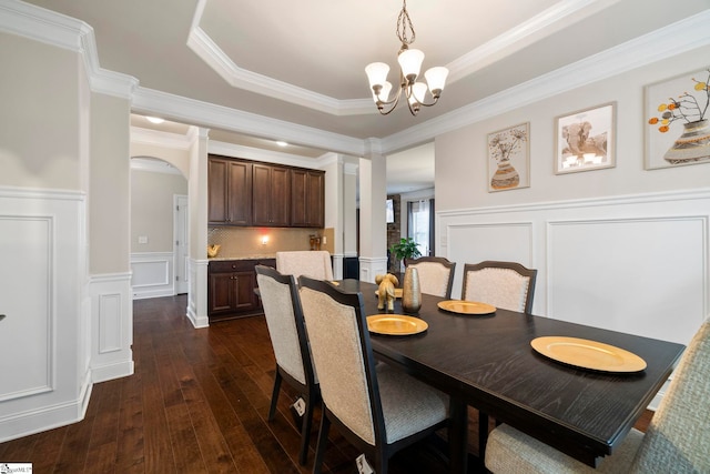 dining room featuring a tray ceiling, ornamental molding, dark wood-type flooring, and a chandelier