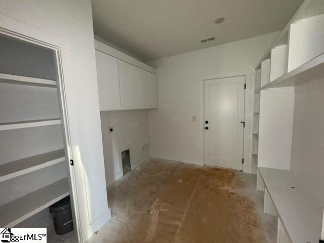 clothes washing area featuring a fireplace, hookup for an electric dryer, and cabinets