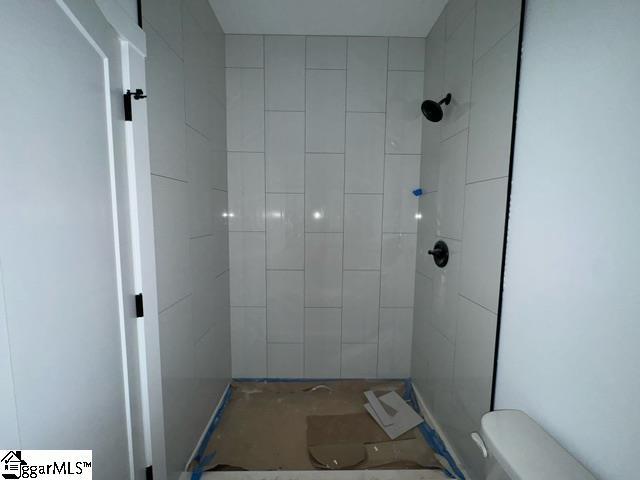 bathroom with toilet and a tile shower