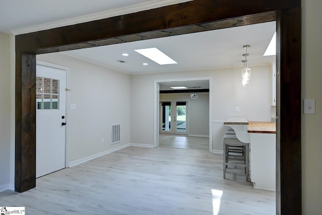 kitchen with a skylight, decorative light fixtures, a breakfast bar, and light hardwood / wood-style flooring