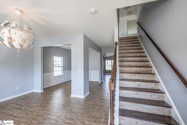 stairway featuring hardwood / wood-style flooring and ceiling fan with notable chandelier