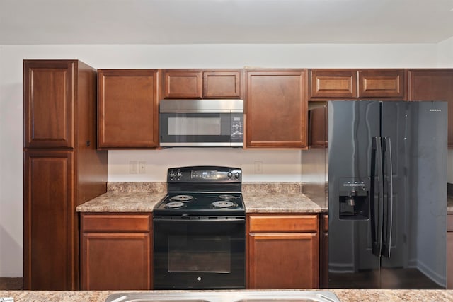 kitchen featuring light stone countertops, fridge with ice dispenser, and black electric range oven